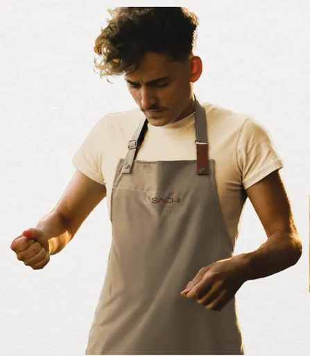 Branded linen apron worn over a cream tee