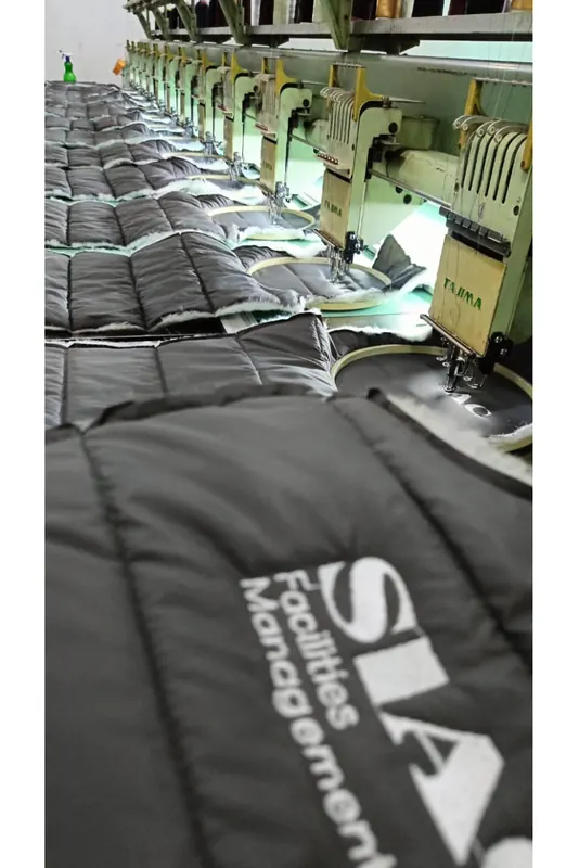 Grey padded jackets with SIAC embroidery on a multi-head embroidery machine