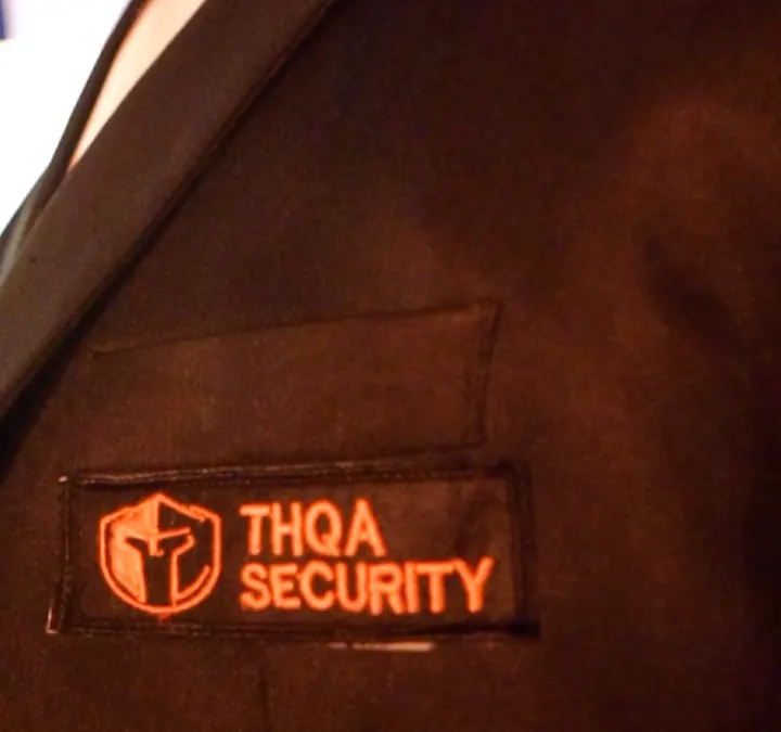 Orange THQA Security woven patch on a dark jacket